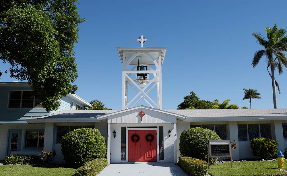 Episcopal Church of the Annunciation exterior in Holmes Beach with white bell tower and red doors